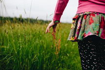 a girl walking through tall grasses 