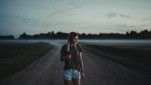 a young woman standing on a dirt road 