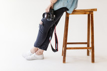Woman with camera sitting on a stool 
