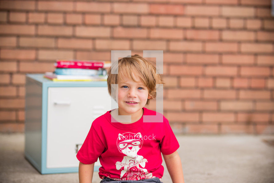 a child sitting in front of a school locker 