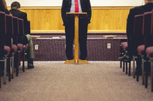 Man in a suit preaching at a podium