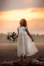 a girl in a white dress holding a bouquet of flowers 