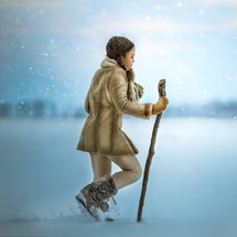 a girl walking through snow with a walking stick 