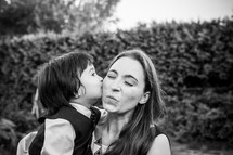 A little boy kissing a woman on the cheek 