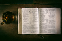a glass mug and open Bible on a table 