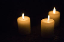 Three white candles with flame.