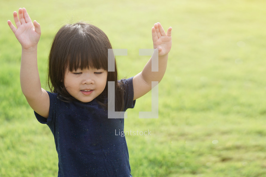 a child with raised hands and worship