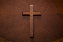 A mahogany wood cross on a similarly textured table top 
