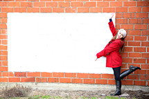 teen girl in a winter coat displaying a blank white sign 
