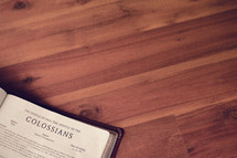 BIble on a wood floor opened to Colossians 
