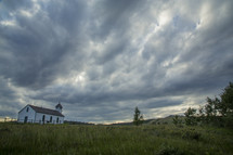 Small white rural church under a stormy dark cloud sky