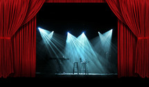 Spotlights on a stage with red curtains.