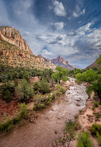 Captured from atop a bridge, Zion's Virgin river leads to The Watchman towering high in the hazy distance. 