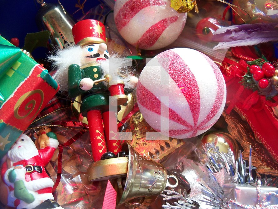 A box of Christmas Ornaments sit patiently waiting to decorate a home for the holidays including a Nutcracker, Santa Claus, Silver Bell, green and red tree ornaments ready to adorn the family tree to usher in the season. 