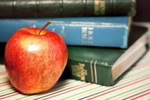 stacked books and an apple 