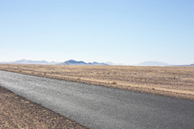 An asphalt road through a barren landscape.