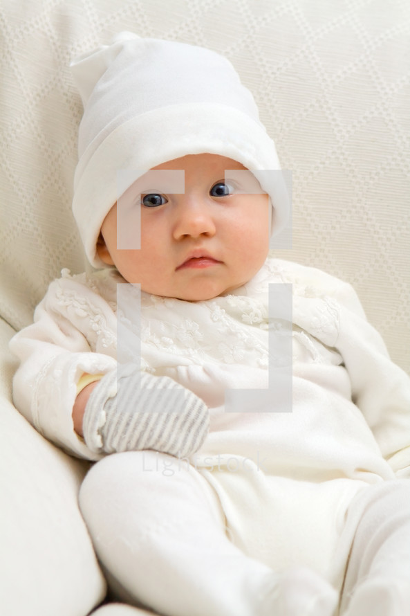 sitting baby dressed in white