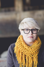 a woman wearing a scarf, reading glasses, and a pixie haircut 