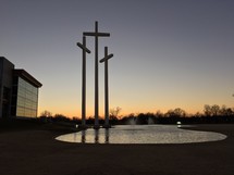 crosses in front of a pond near a church 