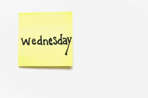 A yellow sticky note with "wednesday" written in black ink on a white background.
