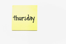A yellow sticky note with "thursday" written in black ink.