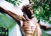 A statue of Jesus showing his wounds where He was pierced by a roman sword and nailed to the cross. This statue is made of bronze of Jesus on a marble cross bearing the sins of the world and taking the place of each of us on the cross. 