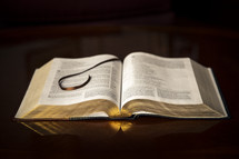 An open Bible and bookmark placed on a wood table top 