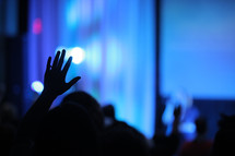 silhouette of a raised hand at a worship service 