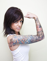 Woman with tattoos on her arm flexing her muscle.