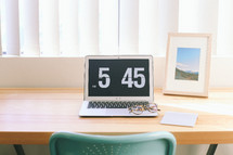A laptop computer on a desk reading, "5:45."
