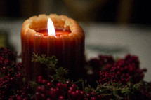 flame on a candle and berry garland 