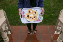 Woman holding tray of pancakes with toppings