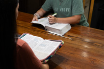 Two young women studying Bible during discipleship group Bible study, pointing and highlighting