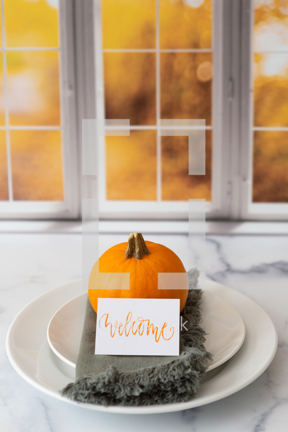 Thanksgiving place setting with the word welcome in front of a kitchen window