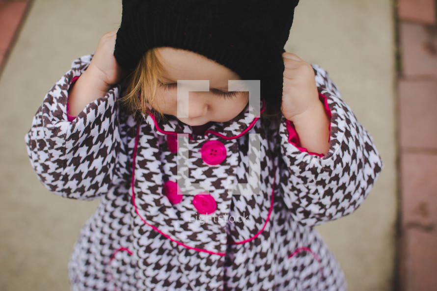 toddler girl putting on a beanie 