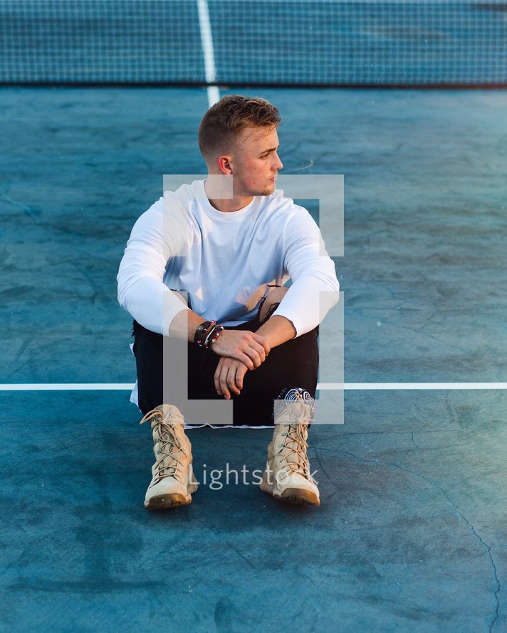 young man sitting on tennis courts 