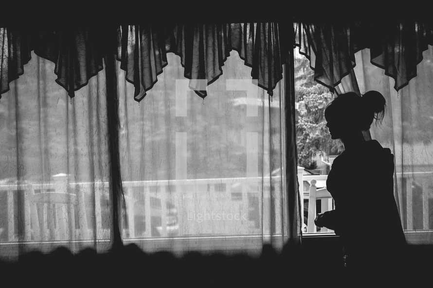 a young woman looking out from behind the curtain