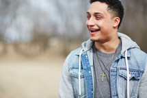 smiling young man wearing a cross necklace 