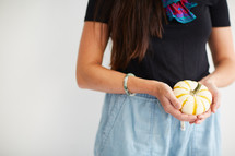 a woman holding a small pumpkin 