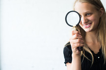 teen girl holding a magnifying glass.