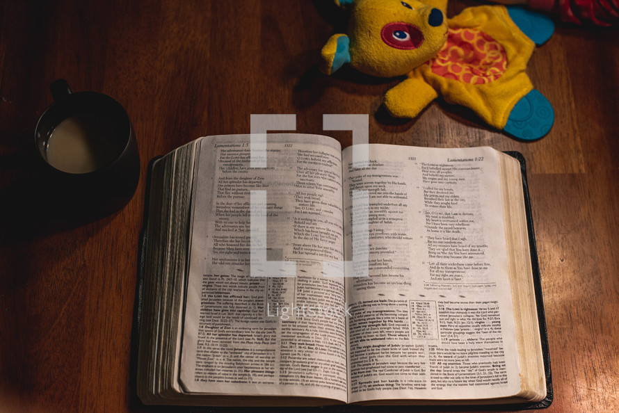 open Bible on a wooden table with a baby toy