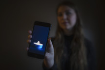 young woman holding image of candle burning in dark room