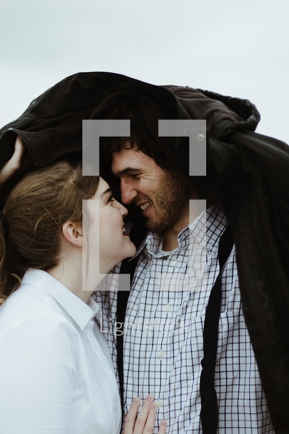 a couple kissing under a coat 
