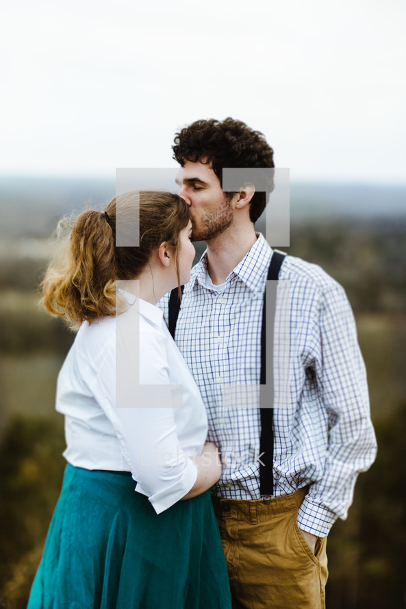 a man kissing a woman on a forehead 