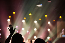 silhouette of a raised hand at a concert.