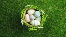 Basket of painted easter eggs on green grass