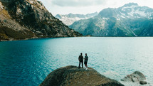men standing on a rocky lake shore 
