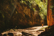 a woman standing at the bottom of a canyon ravine 