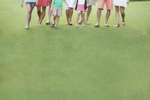 legs of people walking on a golf course 