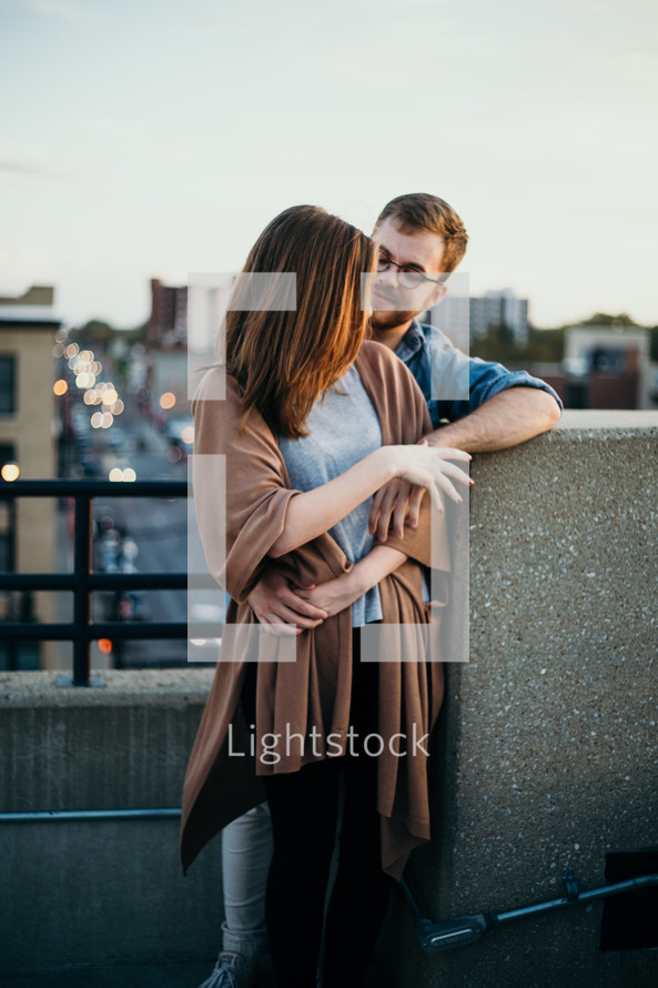 couple standing on a bridge hugging 